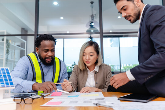 team of multiethnic coworker meeting on solar roof system project with solar panel house model, responsibility of green industry alternative renewable clean environment energy for sustainable business