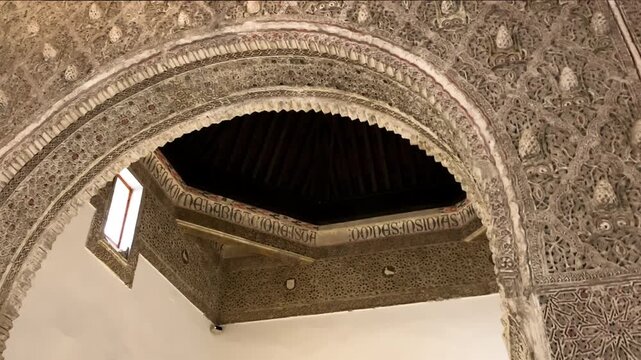 Detailed view of the Mudejar arch inside the Synagogue of Santa Maria la Blanca in Toledo, showcasing intricate plasterwork, geometric patterns, and historic craftsmanship illuminated by soft interior