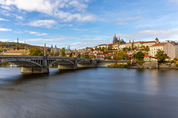 Obraz premium Autumn Panorama of Prague Castle Above the Vltava River with Historic Bridges and the Cityscape of Prague, Czech Republic, Captured in Warm Fall Colors During a Calm Scenic Evening