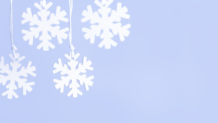 Wooden snowflakes hanging on blue background - winter holiday concept.