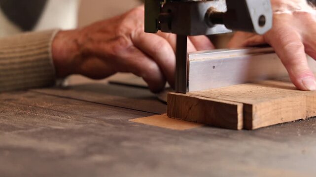 Un menuisier en train d'utiliser une scie &agrave; ruban pour d&eacute;couper une planche dans son atelier.