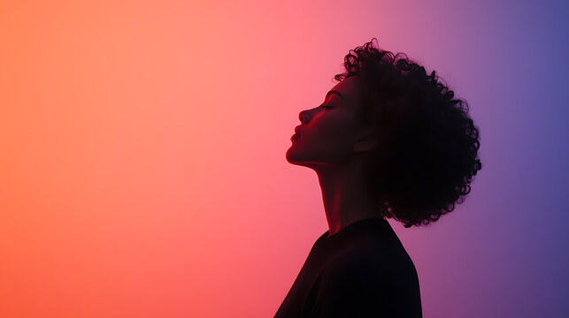 Silhouette of a woman with curly hair against a vibrant gradient background. Her face is tilted up, exuding serenity and peace. The lighting creates a strong contrast and focuses on her features.