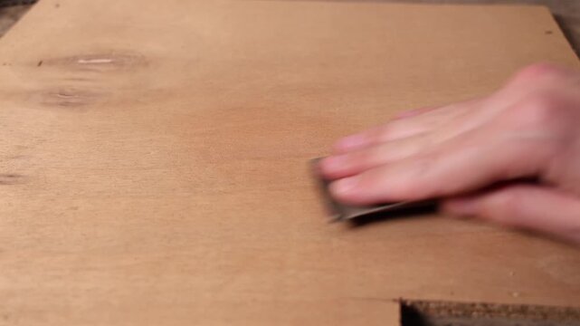 Un menuisier en train de poncer une planche de bois.