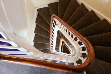 spiral staircase in a modern building resents a spiral staircase. Full-frame composition, brown-beige tone. Realistic style, architectural background