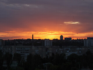 Dramatic sunset over a city skyline with colorful clouds and silhouettes. The vibrant colors of the sunset paint the sky above the city buildings, creating a stunning visual display