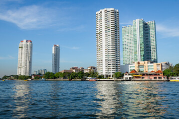 Fototapeta premium View of modern high-rise buildings on the Chao phraya River on a sunny day. Bangkok, Thailand