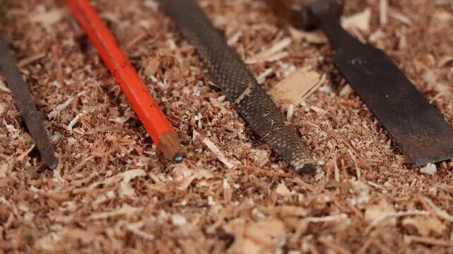 Des outils de menuisier pos&eacute;s sur de la sciure de bois dans un atelier.