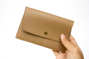 Holding a beige leather clutch purse with snap button closure, isolated on white background.