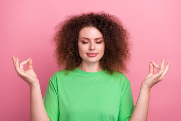 Young woman meditating in a green tshirt against a pink background for lifestyle wellness and fashion advertising