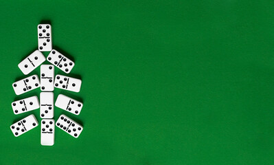 Christmas tree made of domino bones on green background with copy space