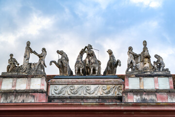 Sculpted figures on the lintel of the Carriage House in Potsdam. A coachman drives horses while attendants flank the carriage, showcasing historic craftsmanship.