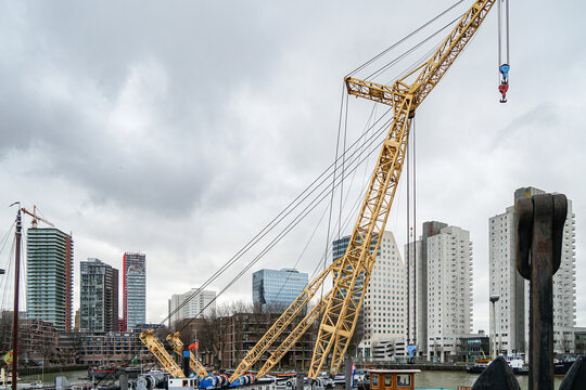 A crane is lifting a large object in front of a city skyline - Powered by Adobe