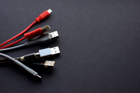 Multiple USB peripheral cables (Universal Serial Bus). USB data and power cables on a dark background. USB cable, charger. Copy space.
