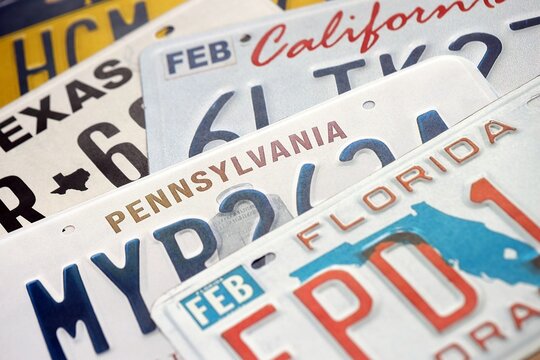 Old US car license plates with various state names close up. Concept of driving in United States. Reaching a car registration