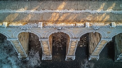 Historic American stone arch bridge adorned with winter bridge frost formations captured from aerial drone perspective showcasing detailed masonry craftsmanship