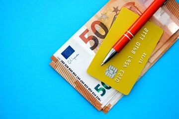 Credit card and pen with euro currency money bills banknotes on light blue background. Business,...