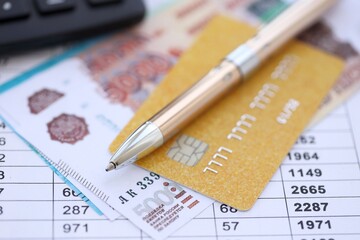 Credit card and pen with russian ruble currency money bills banknotes on calculations document background. Business, financial operations and accounting in Russian Federation