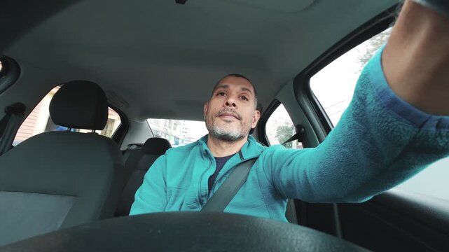Man in his 40s driving a car during his daily commute, filming himself from a selfie perspective