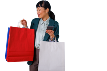 Asian woman shopping using smartphone, holding colorful paper bags, enjoying retail therapy with mobile technology