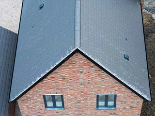 Abstract view of a newly built house with its tiled roof with views of the newly fitted ridge tiles. The house is located on a British housing estate.