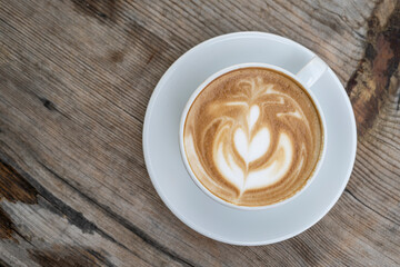 Latte coffee on wooden table. Hot latte cup on rustic wooden surface. Creamy latte coffee on natural wood.