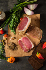 Colorful ingredients lay on a dark surface, showcasing fresh meats and herbs ready for cooking
