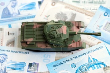 United Arab Emirates dirham currency money bills and toy tank close up. The concept of army funds...