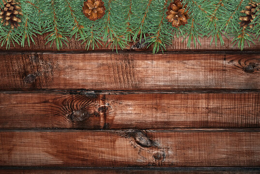 Fir branches with pine cones hanging over rustic wooden planks, creating a natural festive background perfect for Christmas, winter holidays, and seasonal designs
