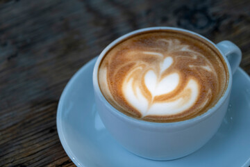 Latte coffee on wooden table. Hot latte cup on rustic wooden surface. Creamy latte coffee on natural wood.