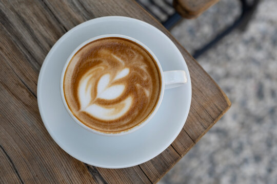 Latte coffee on wooden table. Hot latte cup on rustic wooden surface. Creamy latte coffee on natural wood.