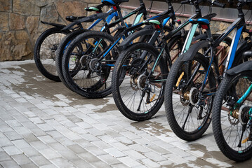 Obraz premium Row of parked bicycles on a wet stone-paved surface.
