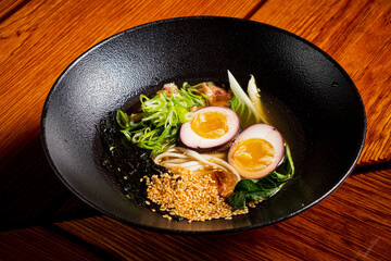 Delicious bowl of ramen with soft boiled eggs, broth, vegetables, and sesame seeds ready to enjoy