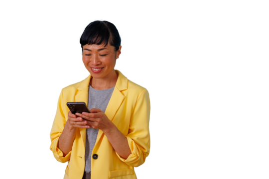Asian woman in yellow blazer smiling and texting on smartphone, communicating and browsing on transparent background