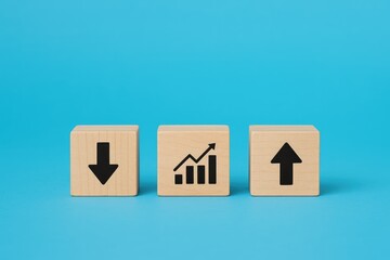 Wooden cubes with up and down arrows and graph icons on blue background, financial metrics