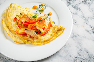 A vibrant vegetable omelette with fresh peppers and zucchini on a white plate