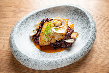 Elegant plate: perfectly cooked fish with clams on flavorful risotto, a true culinary art