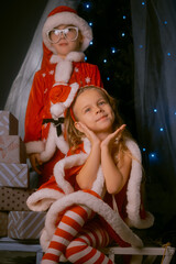 Cute boy and girl in Santa costumes celebrating the holiday season at home.