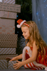 Festive holiday scene with a girl in a Santa outfit surrounded by a large stack of colorful presents.