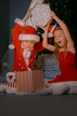 Festive scene of a boy and girl in Santa costumes unveiling a glowing box filled with holiday magic.
