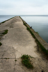 Fototapeta premium Old concrete pier under a cloudy sky in Nida, Curonian Spit and Curonian Lagoon, Lithuania