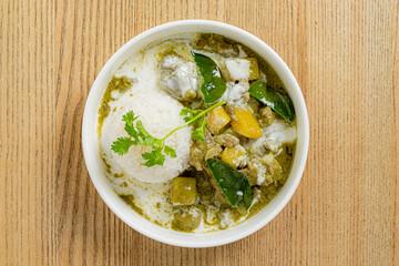 A warm bowl of green curry with rice showcases fresh ingredients and aromatic spices