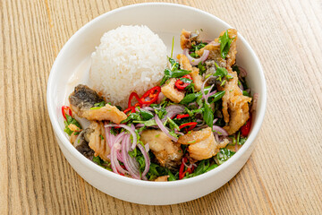 Crispy fried fish with herbs and chilies served alongside steamed rice