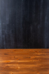 Empty brown wooden table by the black wall. Still life backdrop. Template mock up for display of...