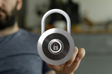 Close up shot of a hand holding a big metal padlock. Concept of safety and data protection.