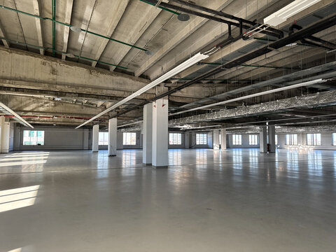 Renovation industrial space or factory floor. Spacious, empty manufacturing bay. Vacant production facility or warehouse space. Warm shell.