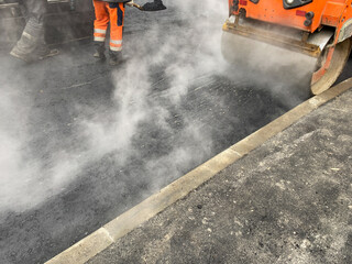 Road works. Partial restoration of road surface. Drum roller laying new asphalt. Steamroller...