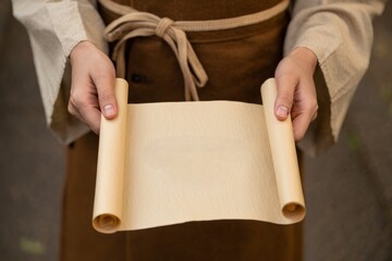Ancient Scroll Held by Hands in Rustic Tunic