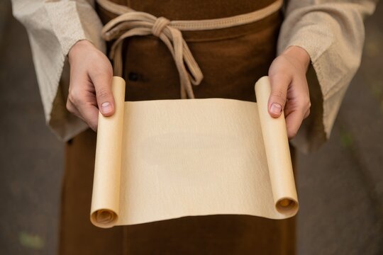 Ancient Scroll Held by Hands in Rustic Tunic - Powered by Adobe