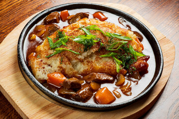A warm bowl of stew featuring tender meat and colorful vegetables, topped with fresh herbs