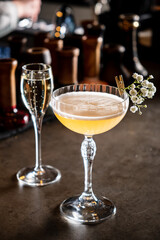 A floral cocktail sits on the counter next to a sparkling bubbly drink